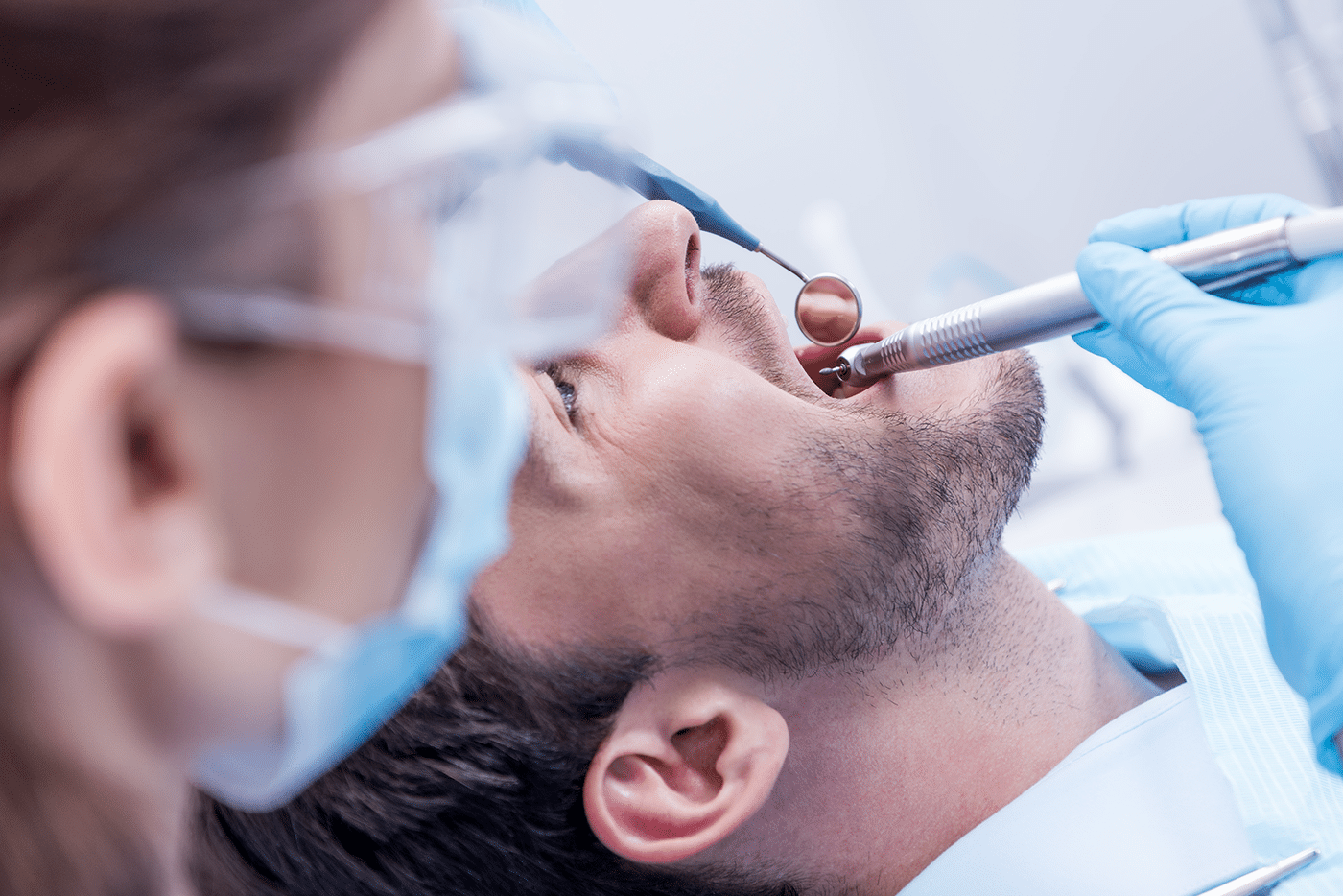 A dentist examines a patient's teeth in preparation for a dental implant procedure