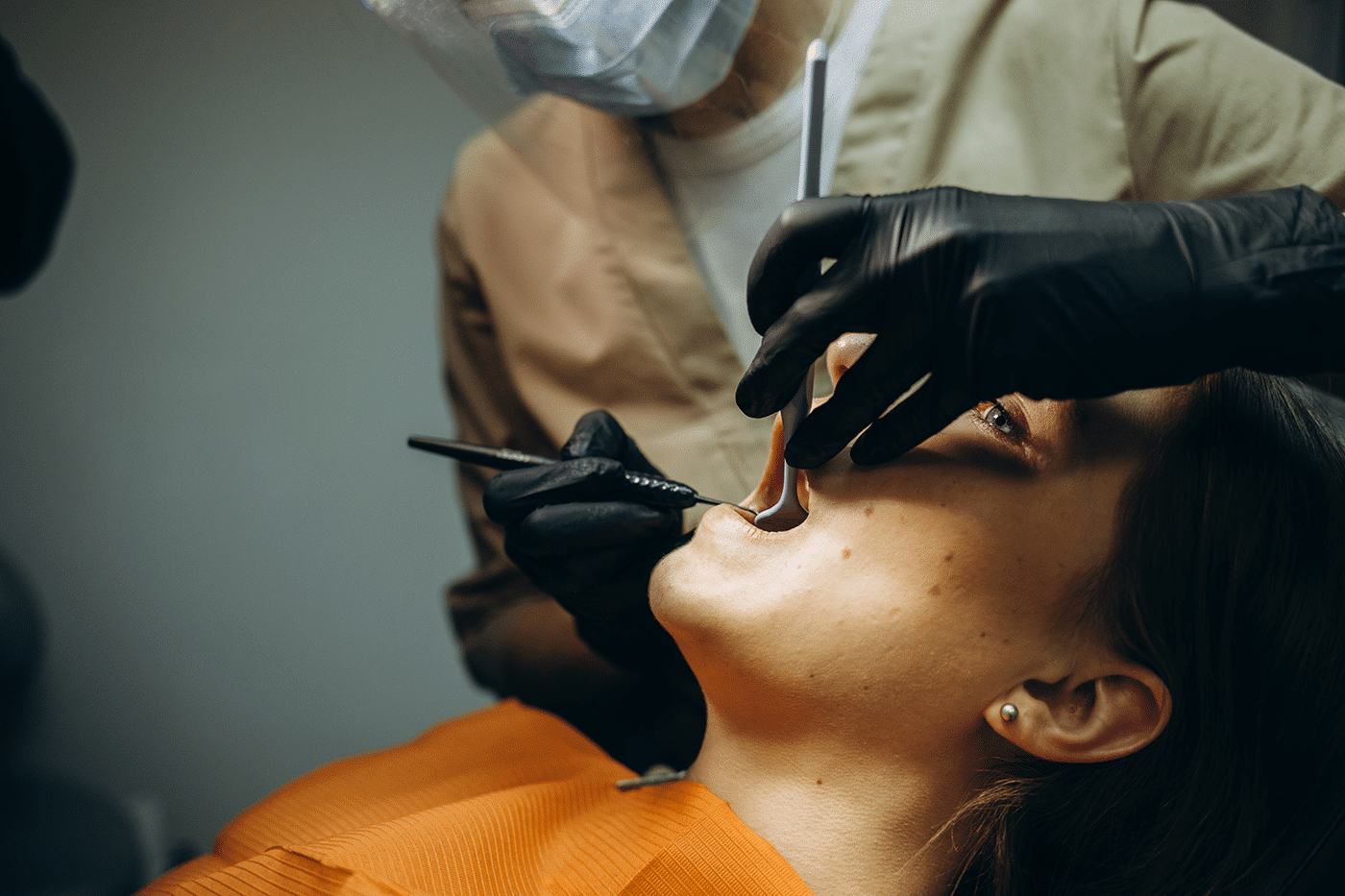 A woman sitting in a dental chair, smiling as a dentist prepares to place a dental implant